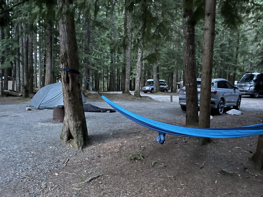 A tent, bivy bag, hammock and SUV at a campsite